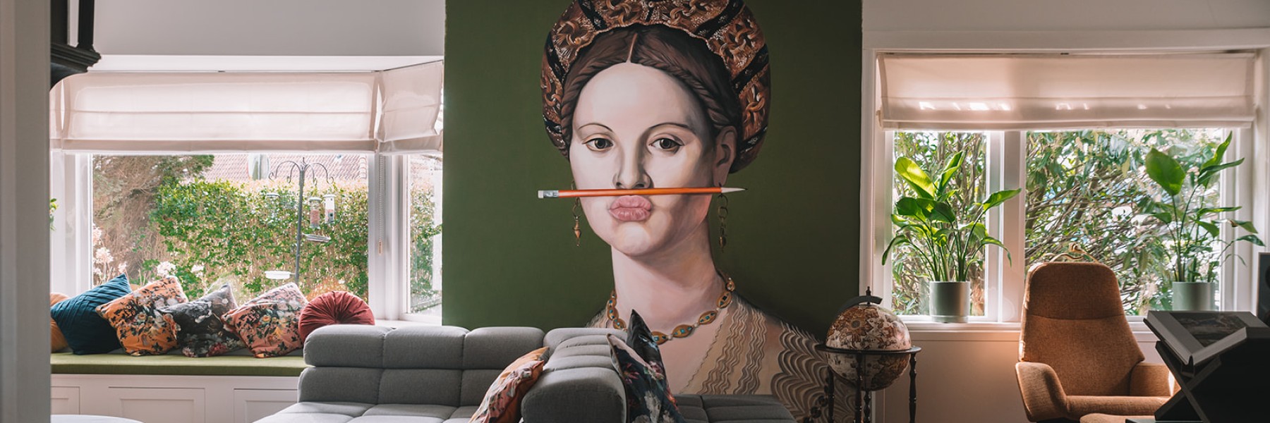 De woonkamer van Sanul en Denise in Zeist met de betoverende  muurschildering van de vrouw met het oranje potlood | Foto: Sheena Schouwink