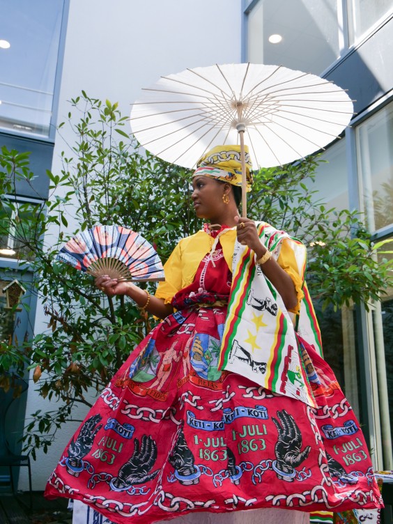 Keti koti outfitDe stof van de koto is een keti koti stof. Het koto model heet broko bere dit betekent gebroken buik, omdat je deze vastmaakt bij je middel en omklapt. De angisa heet opo lanki, want betekent rand omhoog. | Fotografie: Mirjam Michielsen