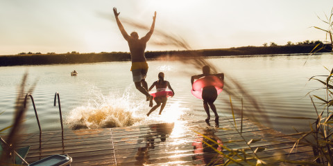 Personen die vanaf een steiger in het water springen en zwemmen