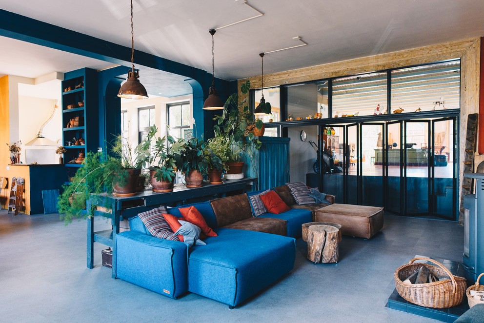 De werkbank, planten en sofa breken de ruimte op in de woonkamer | Foto: Marjon Lukje