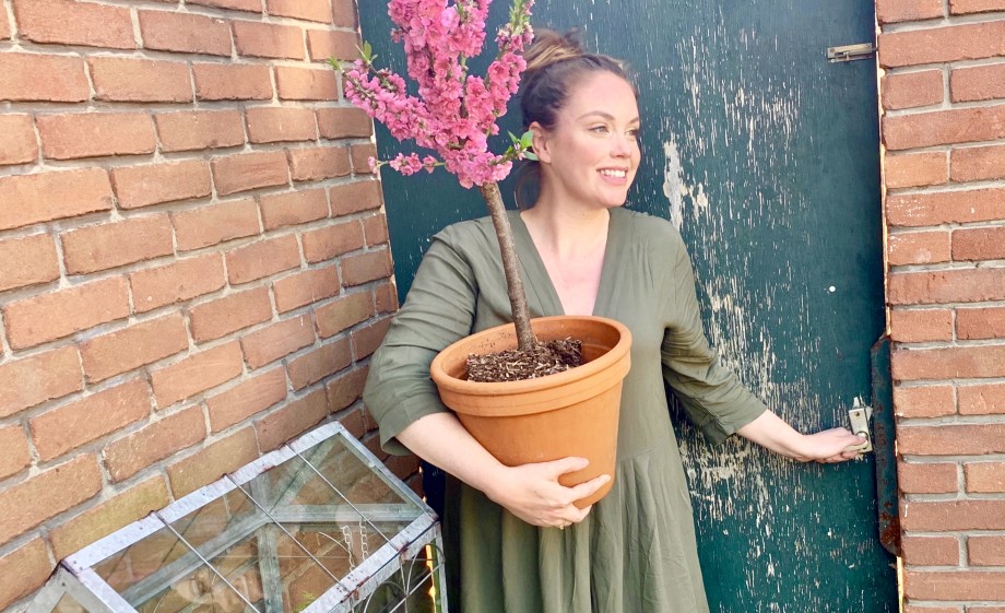 Anne met een perzikboompje in een pot, dit soort kleine boompjes zijn ideaal voor kleinere ruimtes om te tuinieren| Foto: Anne Wieggers